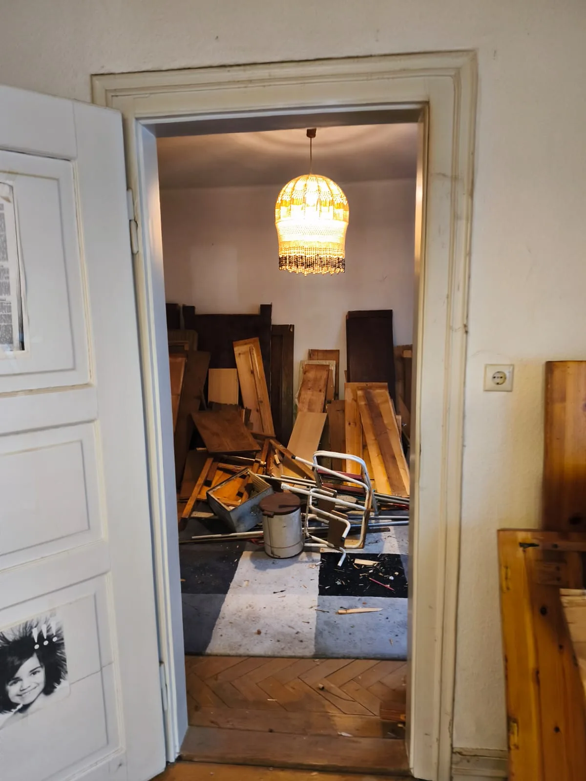 Blick durch eine geöffnete Tür in einen Altbauraum mit Möbelteilen vor der Räumung