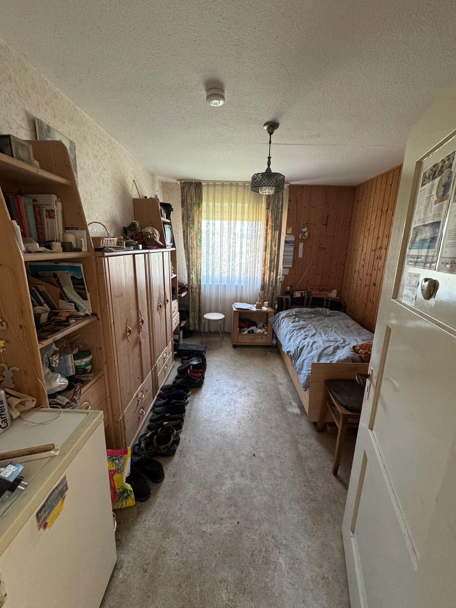 Vollgestelltes Zimmer mit Schrankwand und Regalen vor der Räumung